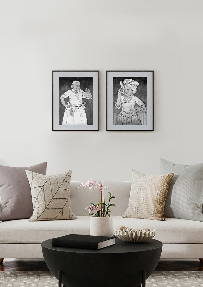 A room with two framed ink paintings: "Garrulous Caregiver" and "One Feisty Lady" by artist Magdalena Olechny. They hang above a couch and coffee table.